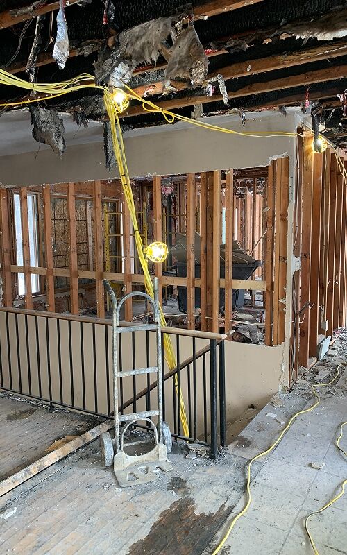 Ceiling and wall opened to framing after a water loss, with drying hose run into the cavity