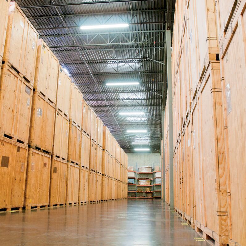 Wooden storage vaults lining the aisle of a contents storage warehouse, where packed-out belongings are held during a restoration