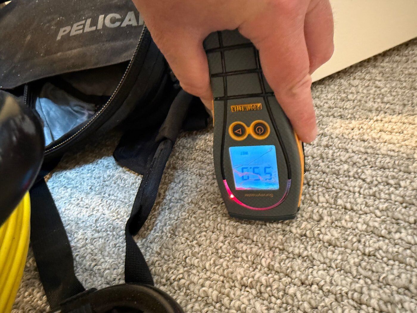 DriForce technician taking a Protimeter moisture reading of 55.9 on wet material during a water loss inspection