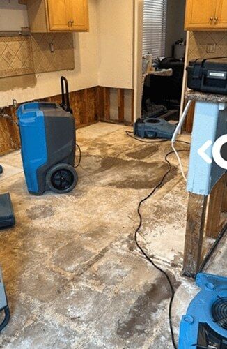 Kitchen stripped to the subfloor with drying equipment running after a water loss