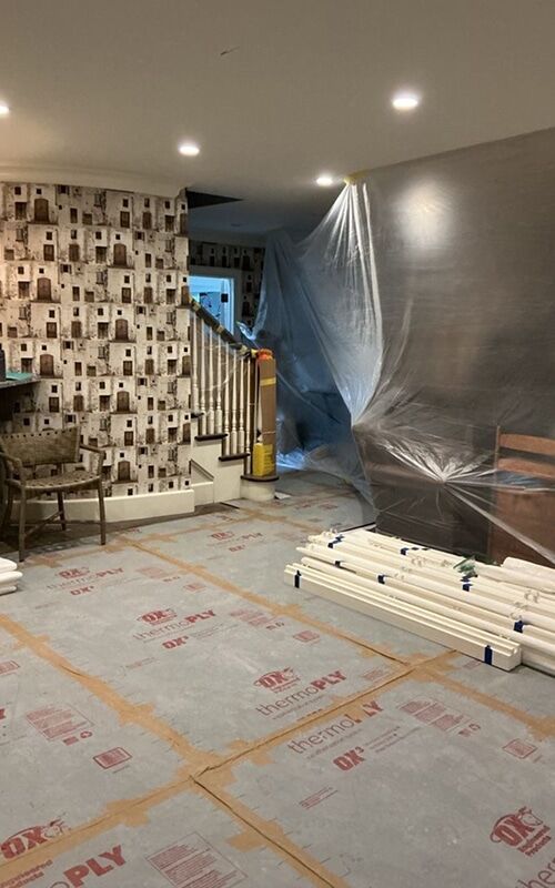 Furniture wrapped in protective plastic with floors covered during contents cleaning and restoration in a Metro Detroit home