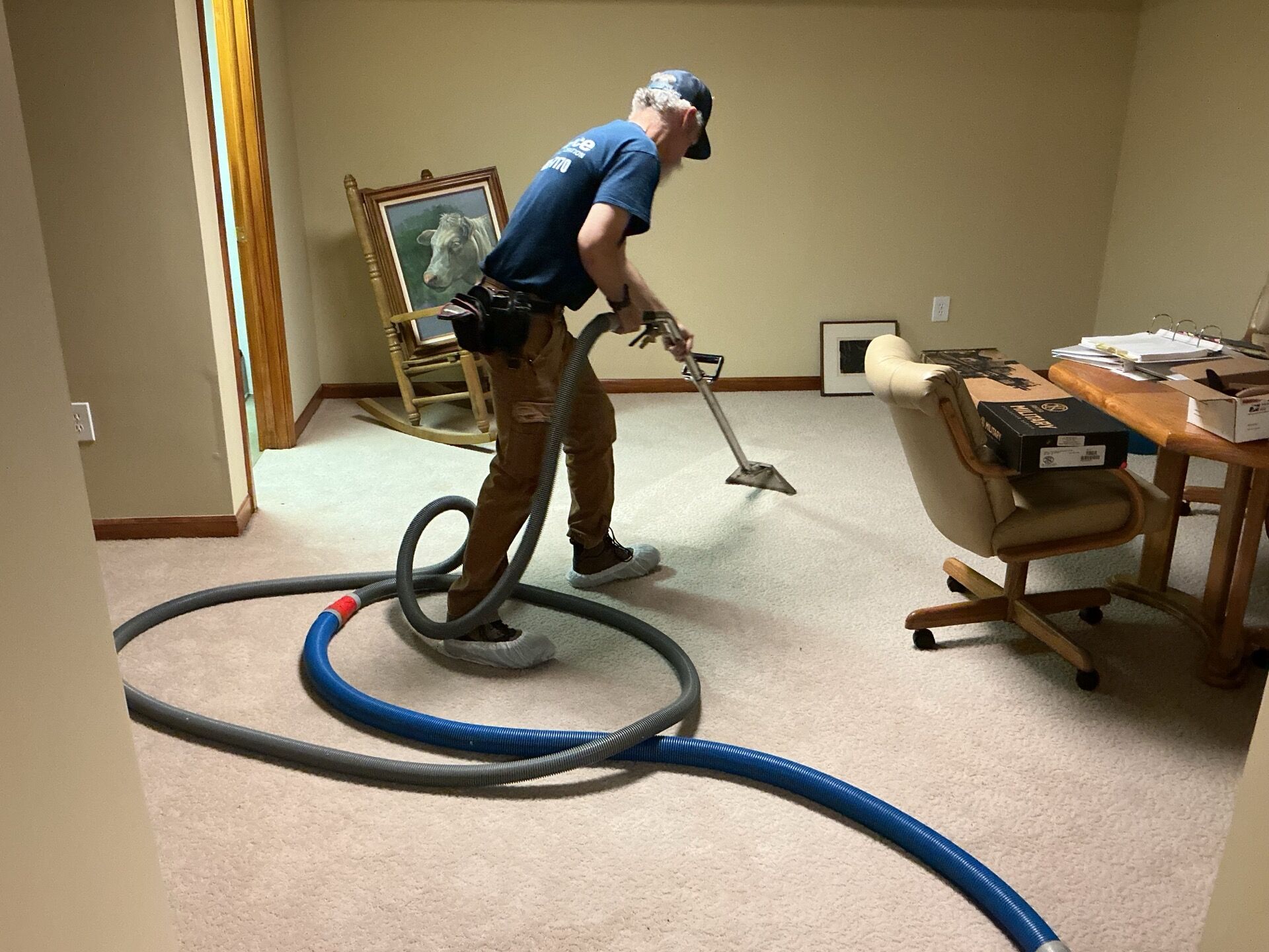 DriForce technician in shoe covers extracting water from carpet during emergency water removal in a Michigan home