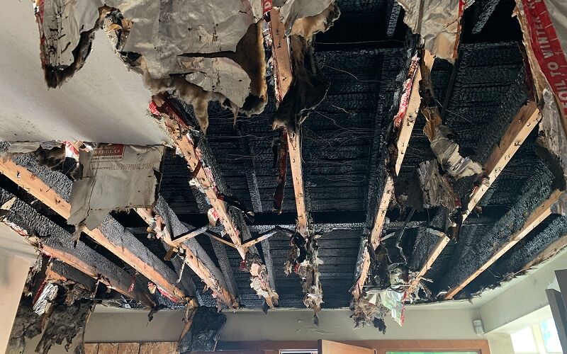 Fire-damaged ceiling and charred joists inside a Michigan home before DriForce restoration