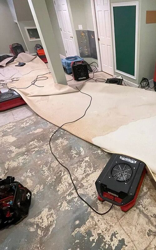 Carpet lifted for drying in a Metro Detroit basement rec room after sump pump failure