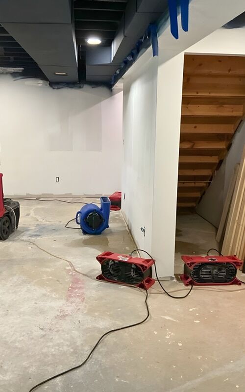 Air movers drying a Michigan basement after a water heater failure flooded the space