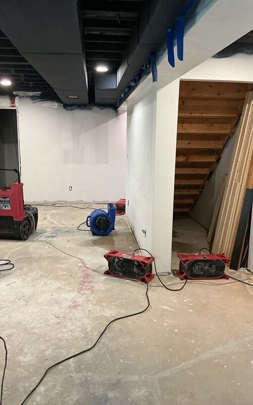 Air movers and dehumidifiers drying a Metro Detroit basement after a water heater failure - DriForce